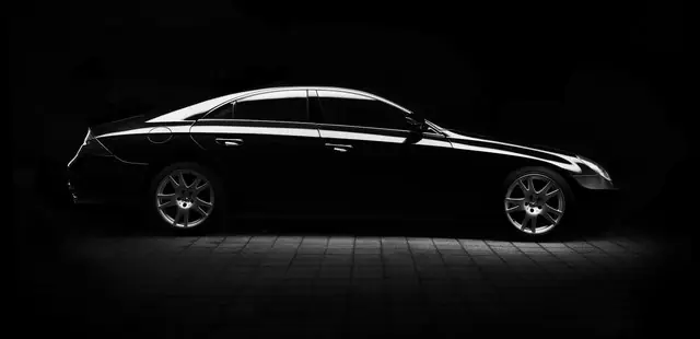 Glossy black saloon car in a dark studio