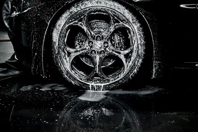 Black alloy wheel covered in foam during a wash